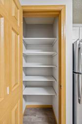 Empty white shelves in a wooden pantry.