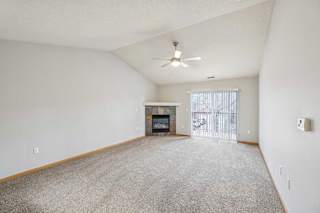 A spacious living room with a fireplace and a ceiling fan.