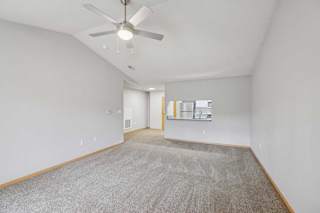 A room with a ceiling fan and carpeted floor.