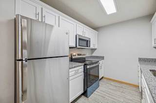 A kitchen with a refrigerator, microwave, oven, and sink.