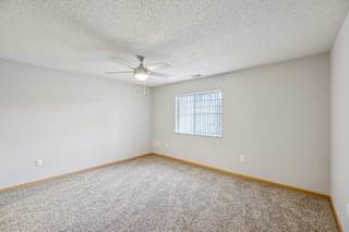 A room with a ceiling fan and a window with blinds.