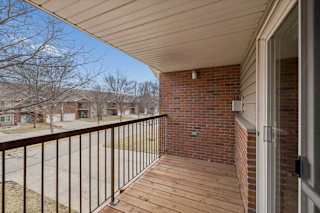 A balcony with a metal railing and a brick wall.
