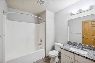 A white bathroom with a toilet, sink, and shower.