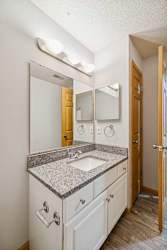 A bathroom with a sink, mirror, and wooden door.