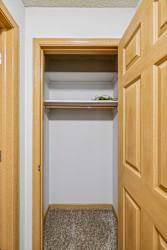 A small closet with a shelf and a pair of glasses on it.