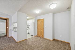 A kitchen area with a refrigerator, sink, and cabinets.