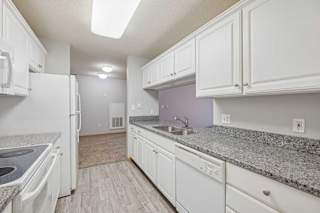 A kitchen with white appliances and cabinets.