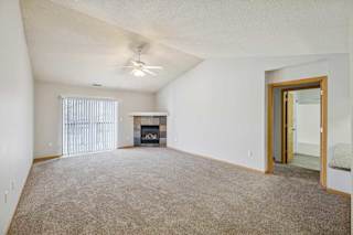 A spacious living room with a fireplace and a ceiling fan.