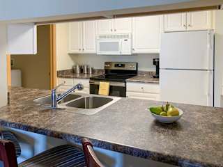 a kitchen with a bar top style counter, a sink, stove, and refrigerator