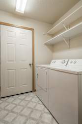 A white laundry room with a door and a washer and dryer.