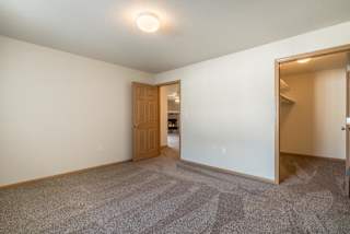 A room with a carpeted floor and a door leading to another room.