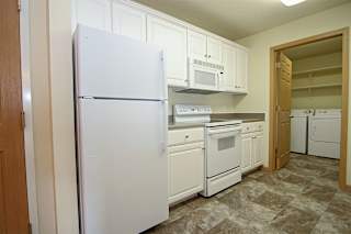 A kitchen with white appliances and cabinets.