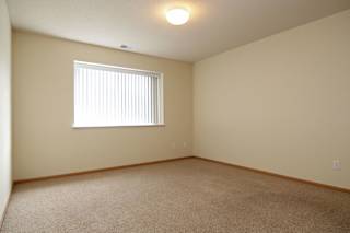 A room with a carpeted floor and a window with blinds.