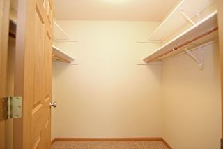 A hallway with a door on the left and a shelf on the right.