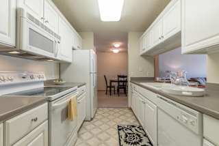 A kitchen with white appliances and cabinets.