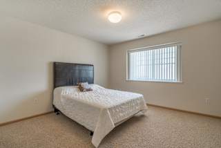 A bedroom with a bed, a window with blinds, and a wooden headboard.