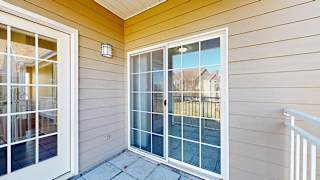 a balcony with a door to the kitchen and a sliding glass door to the primary bedroom