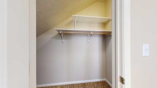 a slanted closet with a built-in shelves and hanging rod