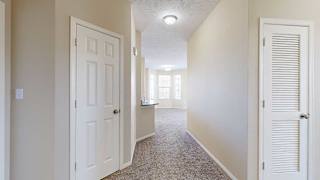 a hallway with a coat closet and a small mechanical closet