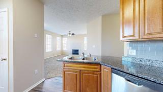 a kitchen with granite countertops, a tile backsplash, wooden cabinets, and a stainless steel sink