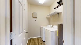 a laundry room with a full-sized washer and dryer with overhead shelving