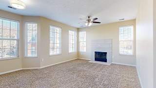 a large living room featuring multiple windows, a modern tiled fireplace, and carpeted flooring
