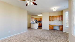 an open-concept living and dining area with carpeted flooring, a ceiling fan, and a built in desk with storage