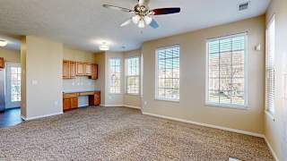 a living room with carpet, a ceiling fan, a built-in desk, and large windows