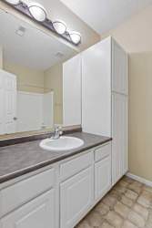 A bathroom with a sink, mirror, and cabinets.