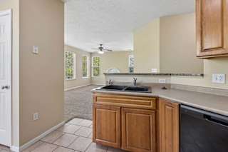 A kitchen with wooden cabinets and a black dishwasher.