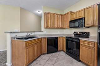 A kitchen with wooden cabinets and black appliances.