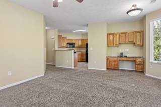 A spacious living room with a kitchenette and a ceiling fan.