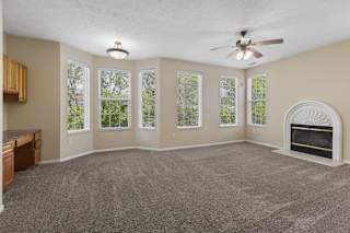 A spacious living room with a fireplace and a ceiling fan.