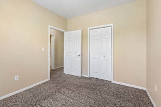 A room with two white doors and carpeted floor.