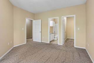 A room with a carpeted floor and a white door.