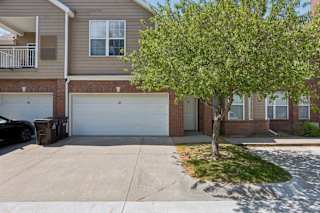 A tree is in front of a house with a garage door.