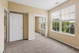 A room with a white door, carpeted floor, and a window with blinds.