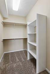 A white shelving unit in a room with carpeted floor.