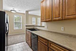 A kitchen with wooden cabinets and a black refrigerator.