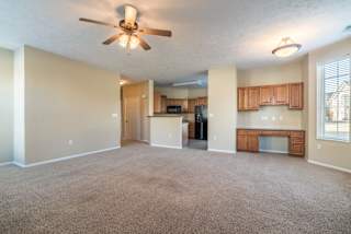A spacious living room with a ceiling fan and carpeted floor.