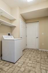 A white washing machine in a room with a door and a wall.