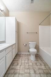 A white toilet sits in a bathroom with a white sink and a white bathtub.
