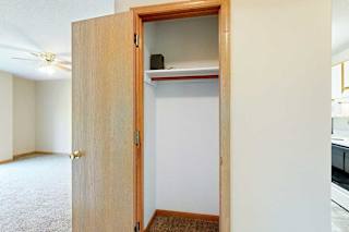 Coat closet with hanging rod and upper shelf, located off the main living area.
