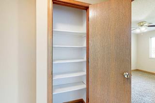 Linen closet with built-in white shelving for organized storage in the apartment hallway.
