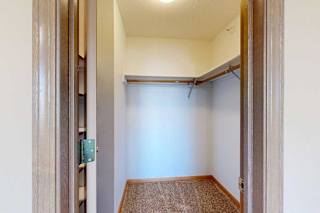 Walk-in bedroom closet with carpet flooring, hanging rods, and overhead shelf for additional storage.