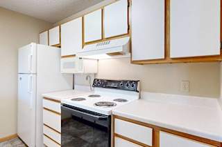 Kitchen with white oven, over-the-range microwave, refrigerator, and ample cabinet storage.