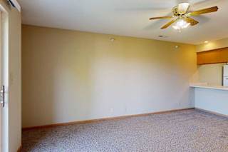 Carpeted living area with large sliding glass door, vertical blinds, and access to private balcony.