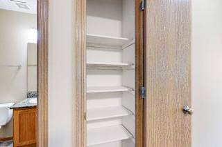 Linen closet with multiple white built-in shelves located just outside the bathroom in this apartment interior.