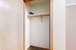 Coat closet with single hanging rod and upper shelf, wood-trimmed doorway, and carpeted flooring.