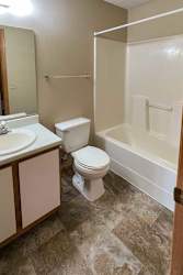 a bathroom with a vanity sink, a towel rack, and a tub shower